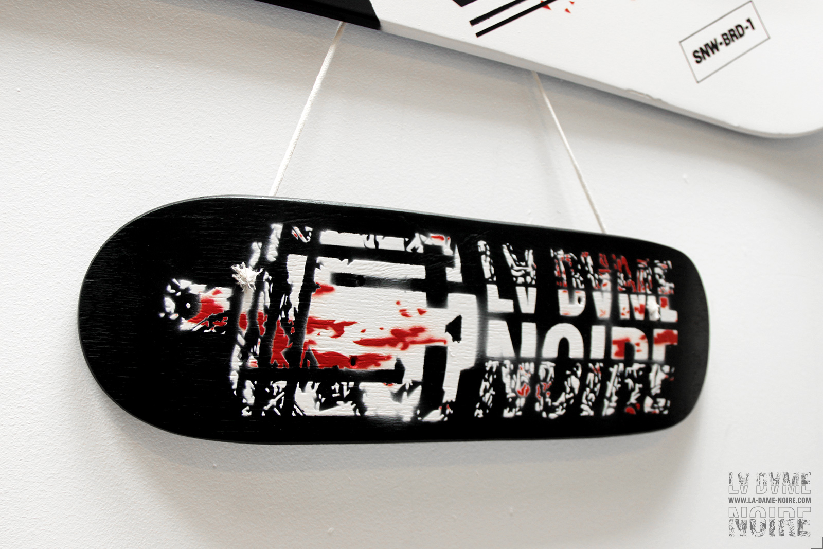 Tiny skateboard painted in black and white with a skull and words La Dame Noire