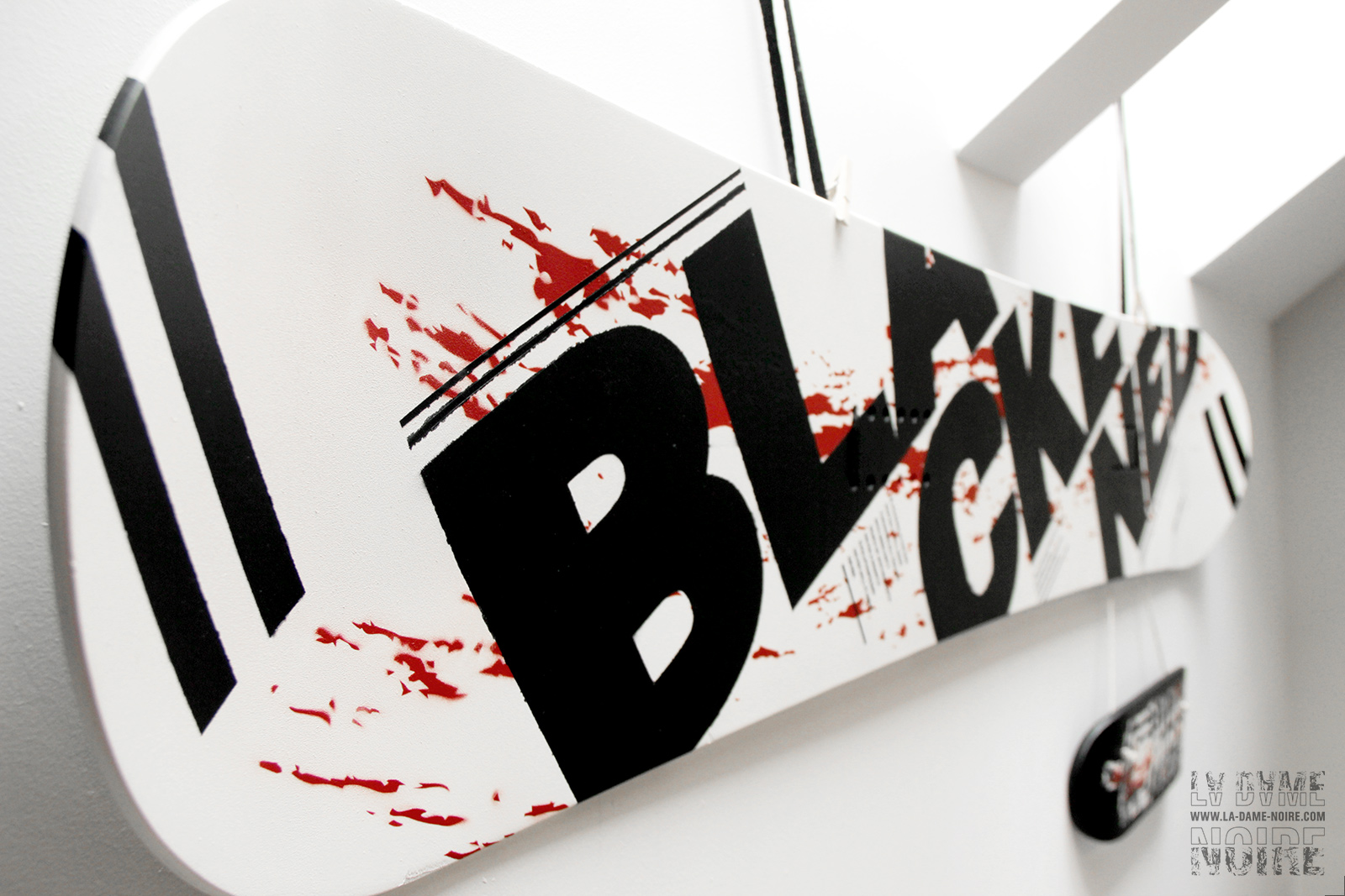 Details of the snowboard painted in black, white, red, and the word Blackened in big bold letters