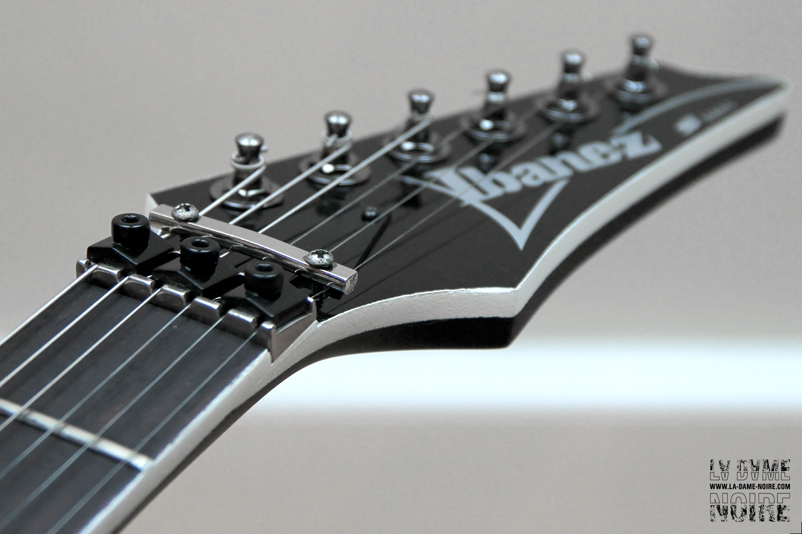 Photo de la tête de la guitare repeinte en noir avec un contour blanc